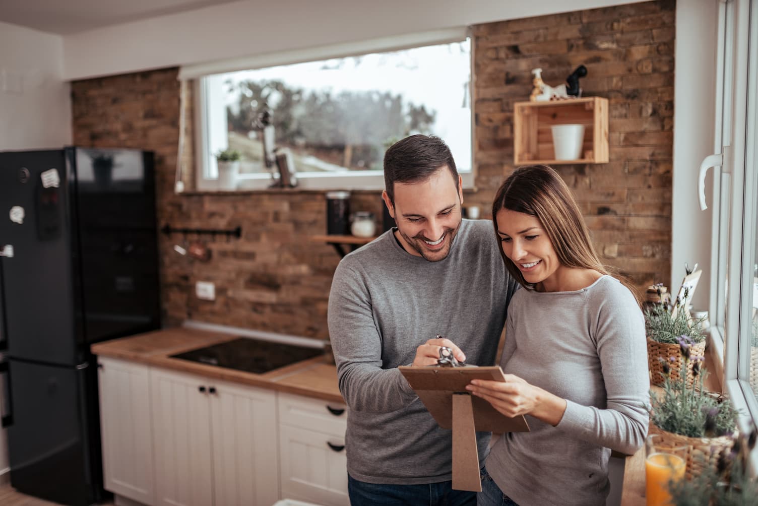 Mann und Frau schauen in Küche auf Klemmbrett